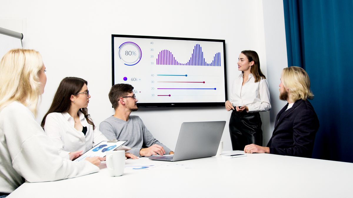 Equipe reunida analisando um dashboard na tela